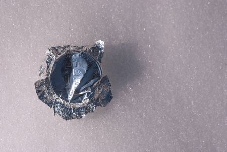 inflation, a wrapper made of foil in the form of bitcoin lies on the snowの写真素材