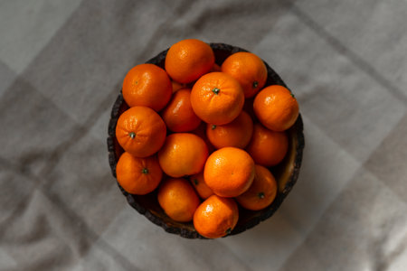 Basket with tangerine or orange fruit on a gray plaid background.の写真素材
