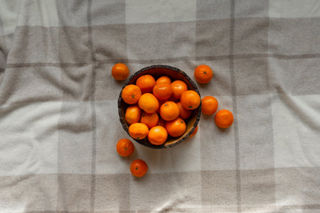 Basket with tangerine or orange fruit on a gray plaid background.の写真素材