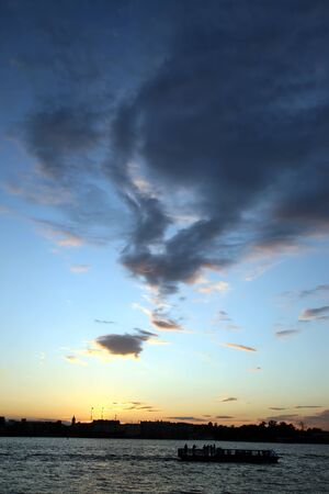 sunset over the city by a river with a floating boatの写真素材