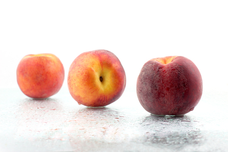 three ripe peaches in the water droplets on white backgroundの写真素材