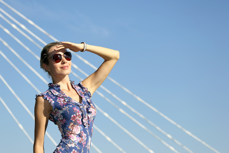 young beautiful girl in sunglasses looking at the sun on the blue sky backgroundの写真素材