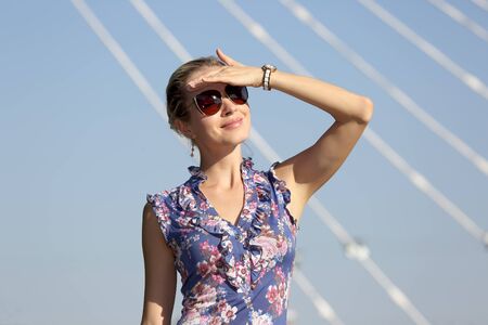 young beautiful girl in sunglasses looking at the sun on the blue sky backgroundの写真素材