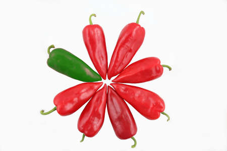 one green and seven red sweet peppers on a white backgroundの写真素材