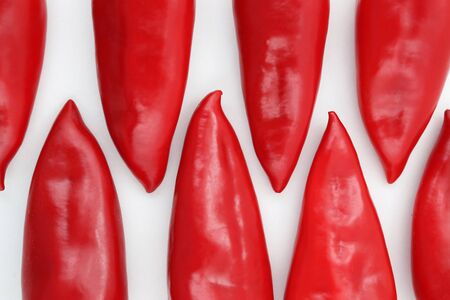 a group of red sweet peppers on a white backgroundの写真素材