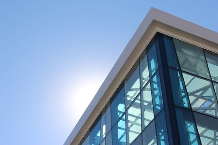 the transparent facade of the building against the sky and the sunの写真素材