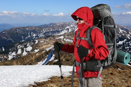 the equipped with traveler in a red jacket stands on the hillsideの写真素材