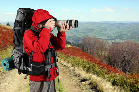 the tourist in a red jacket with a gray backpack taking picturesの写真素材