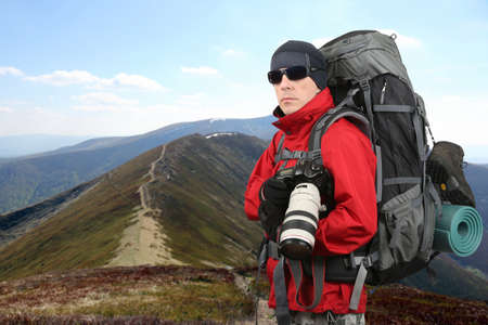 equipped with the traveler photographer in the red jacket on the mountain slopeの写真素材