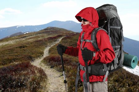the equipped with traveler in a red jacket stands on the hillsideの写真素材