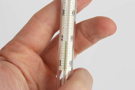 thermometer in hand closeup on a light backgroundの写真素材