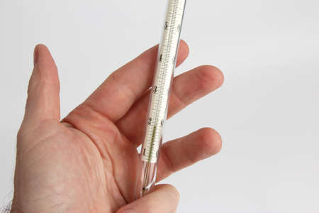 thermometer in hand closeup on a light backgroundの写真素材