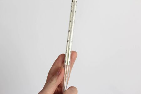 thermometer in hand closeup on a light backgroundの写真素材
