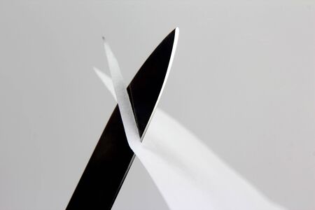 the blade of a sharp knife cut across the white paperの写真素材