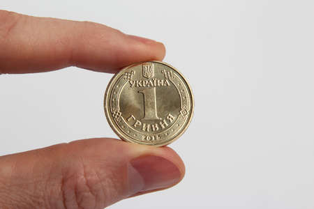 the arm holding one of the Ukrainian coin on a light background