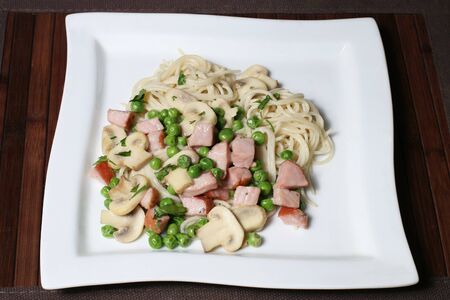 the spaghetti with mushrooms, ham and peasの写真素材