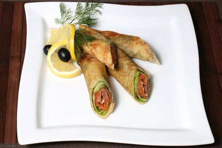 the pancakes stuffed with salmon and greens with olives and lemonの写真素材