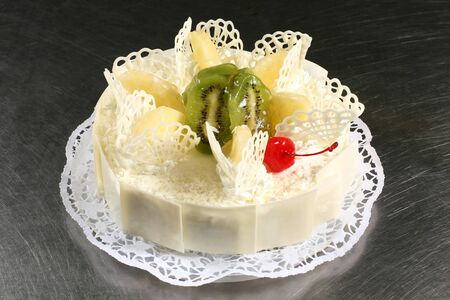 sweet white cake with pineapple and kiwi on a gray backgroundの写真素材