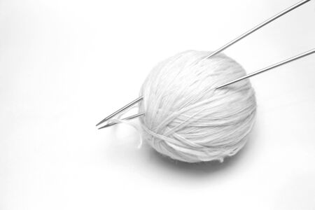 ball of white wool yarn with knitting needles on white backgroundの写真素材