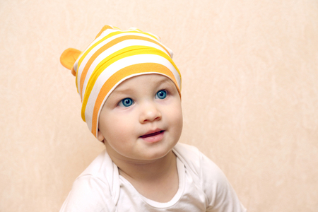 portrait of little baby with beautiful blue eyes, in a bright striped hatの写真素材