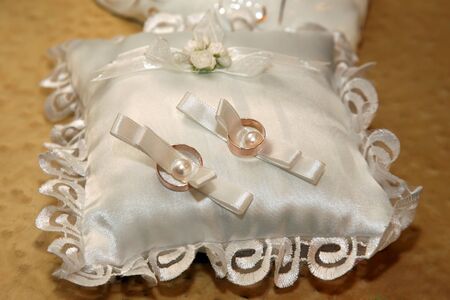 wedding rings lie on a beautiful white pillowの写真素材