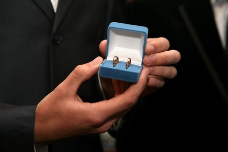the groom holds a box with gold wedding rings close up