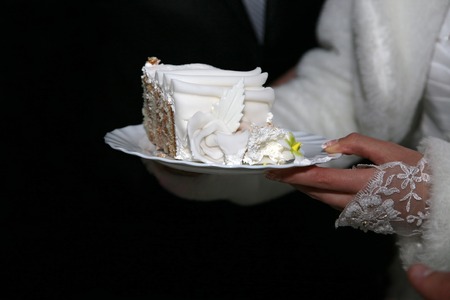cut a piece of wedding cake in the hands of the brideの写真素材