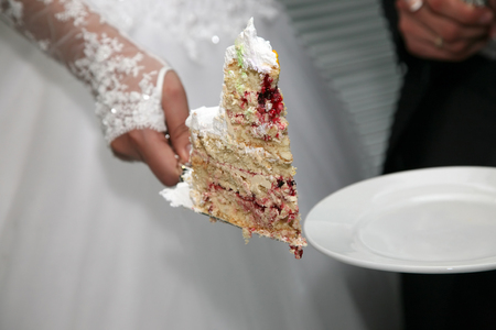 cut a piece of wedding cake in the hand of the brideの写真素材