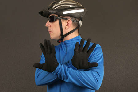 cyclist with glasses looking to the side and shows a negative sign with handsの写真素材