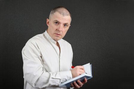 attentive man in the bright shirt is going to write in the book