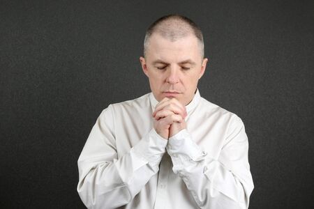 white man with closed eyes and folded in the face handsの写真素材