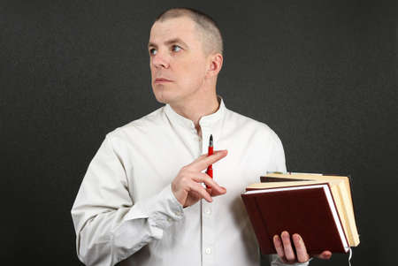 white man with a pen and books in their hands looking to the sideの写真素材