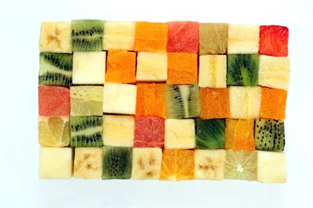 fresh fruits cut in cubes stacked together on white background