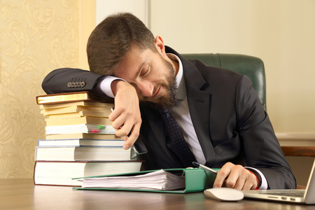 business man tired of working with books and documentsの写真素材
