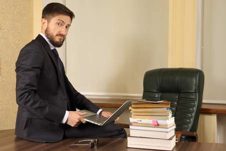 successful business man sitting at office table and working with laptopの写真素材
