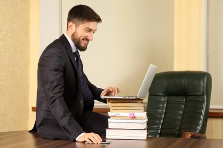 successful business man sitting at office table and working with laptopの写真素材