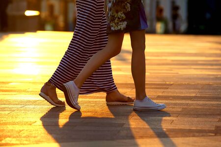 legs of two people walking on the background of sunlightの写真素材