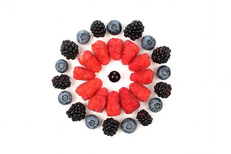raspberries, blackberries, blueberries laid out in the shape of circle on white background