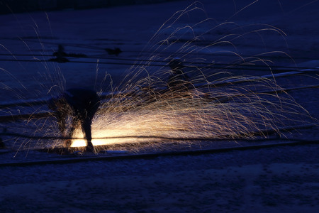 worker making repairs at night on metal rails