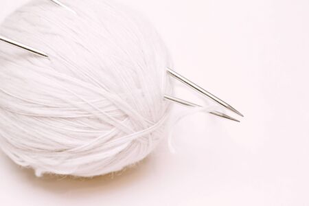 ball of white wool yarn with knitting needles on white backgroundの写真素材