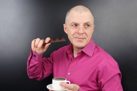 happiest man in the pink shirt with chocolate and a Cup of coffee in hand
