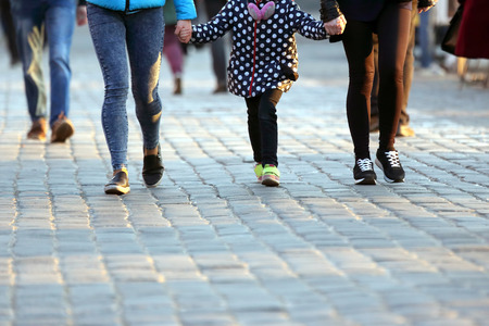 people holding hands walking on the pavement
