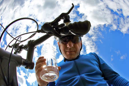 cyclist with a bike with a bottle of water on sky backgroundの写真素材