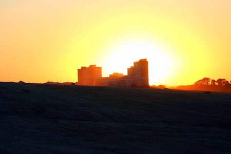 the silhouette of the house in field on sunset backgroundの写真素材