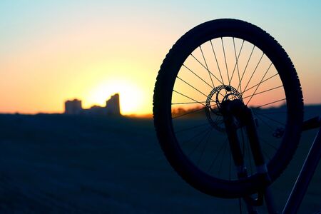 the silhouette of the bike wheel at sunsetの写真素材