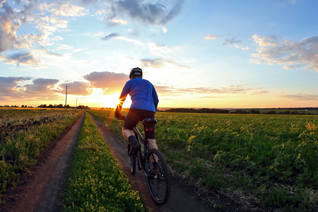 cyclist rides a bicycle on a track at sunsetの写真素材