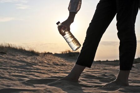 girls hand holding a bottle of water in the desertの写真素材