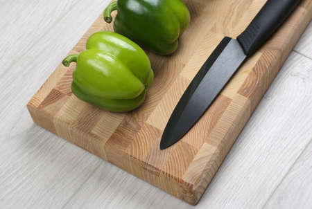 sweet peppers with a ceramic knife on a wooden boardの写真素材