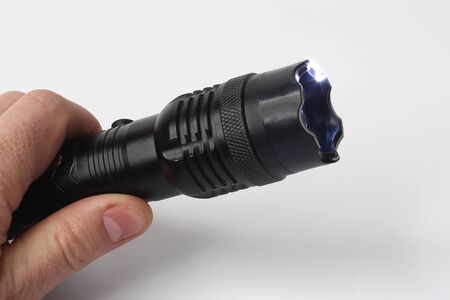 working Taser in hand on white background