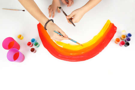 Child's hands draws a rainbow on a white backgroundの写真素材